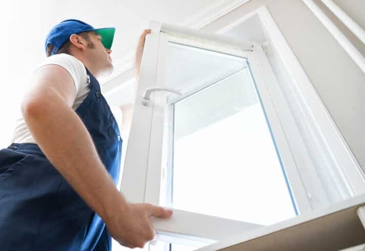 Professional handyman installing window at home.