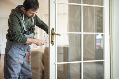 A-man-with-screwdriver-is-replacing-the-front-entry-door A man with screwdriver is replacing the front entry door